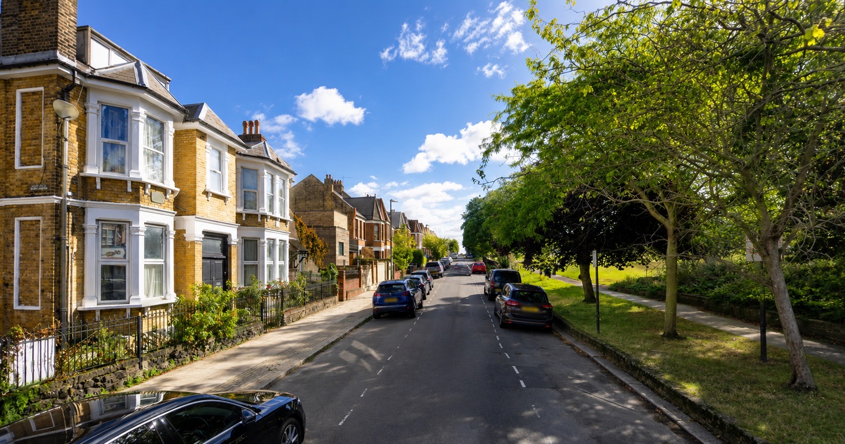 Sunny North London street of brick terraces beside a green park